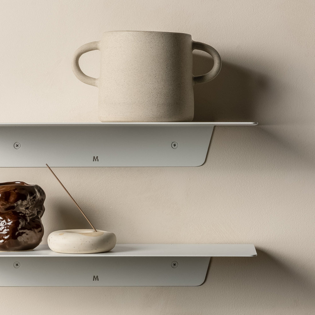 Close-up of white FOLD Ledges holding a large mug and ceramic pieces