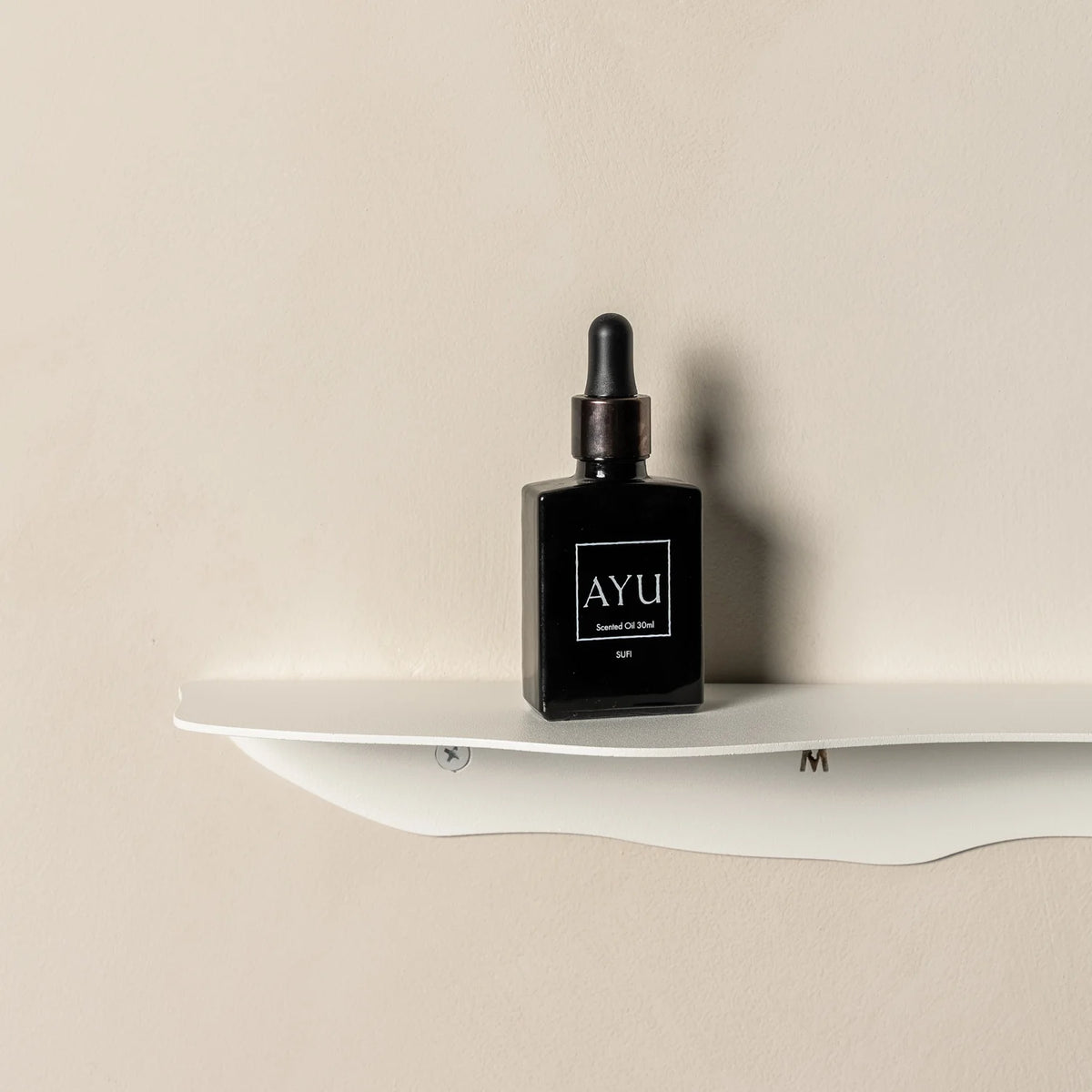 White wavy shelf on beige plaster seen straight on, holding a single small dark bottle