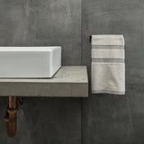 A Scandinavian bathroom with a Made of Tomorrow FOLD Hand Towel Holder ∙ Black, showcasing a bathroom sink and a towel hanging on the wall.
