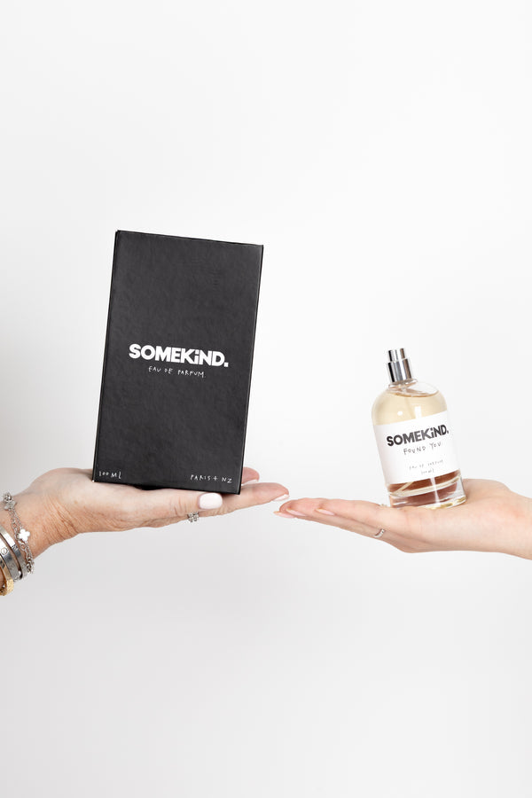 Hands holding the black box and the perfume bottle on white