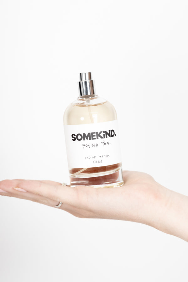 Hand holding the Found You perfume bottle on white