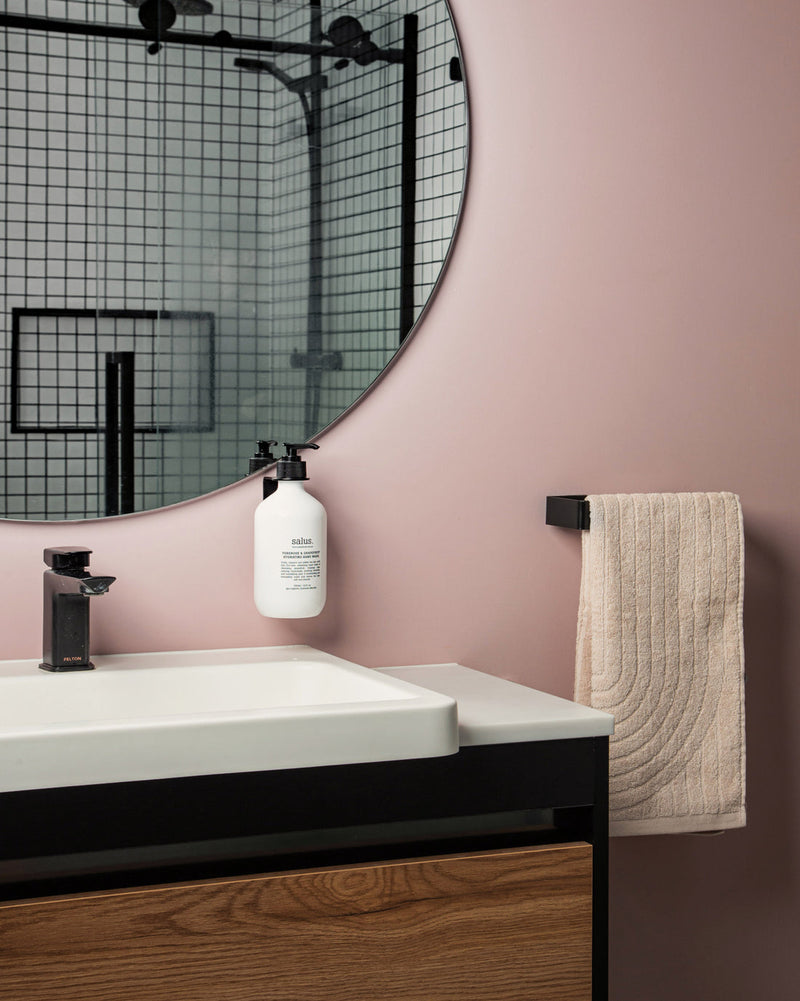 A Scandinavian bathroom featuring a pink wall and a black sink. The bathroom is accessorized with the Made of Tomorrow FOLD Hand Towel Holder ∙ Black, adding a touch of functionality to the stylish Bathroom range.