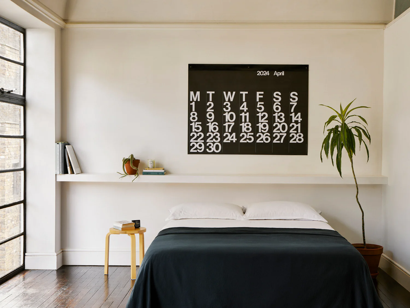 A modern bedroom with a bed and a 2024 Stendig Calendar - PREORDER.