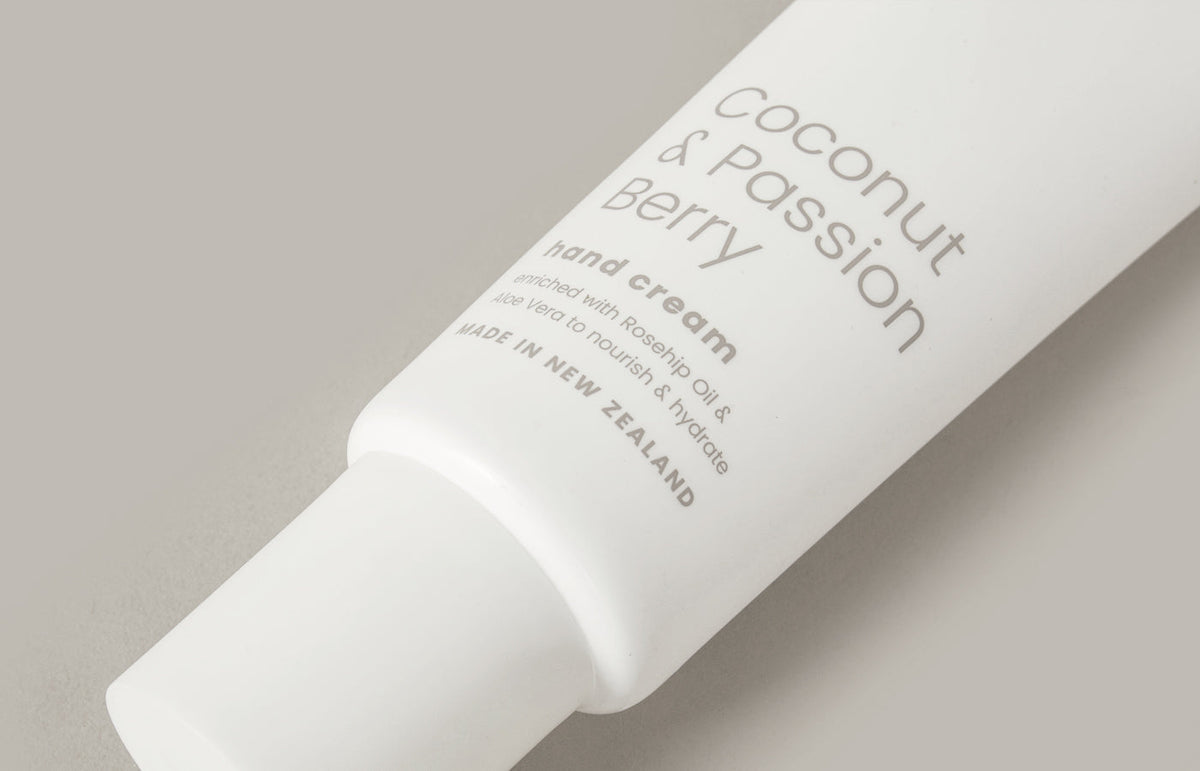 Close crop of the Coconut & Passion Berry tube label on a warm grey surface