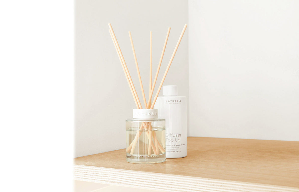 Naturals diffuser and its top up bottle on a pale timber shelf