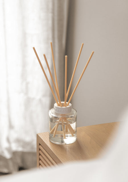 Naturals diffuser on the corner of a fluted timber cabinet by a sheer curtain