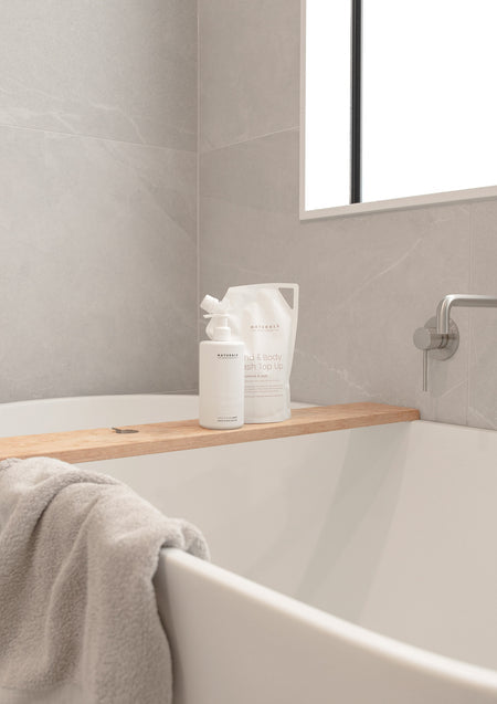 Naturals refill pouch on a timber bath caddy over a freestanding white bath