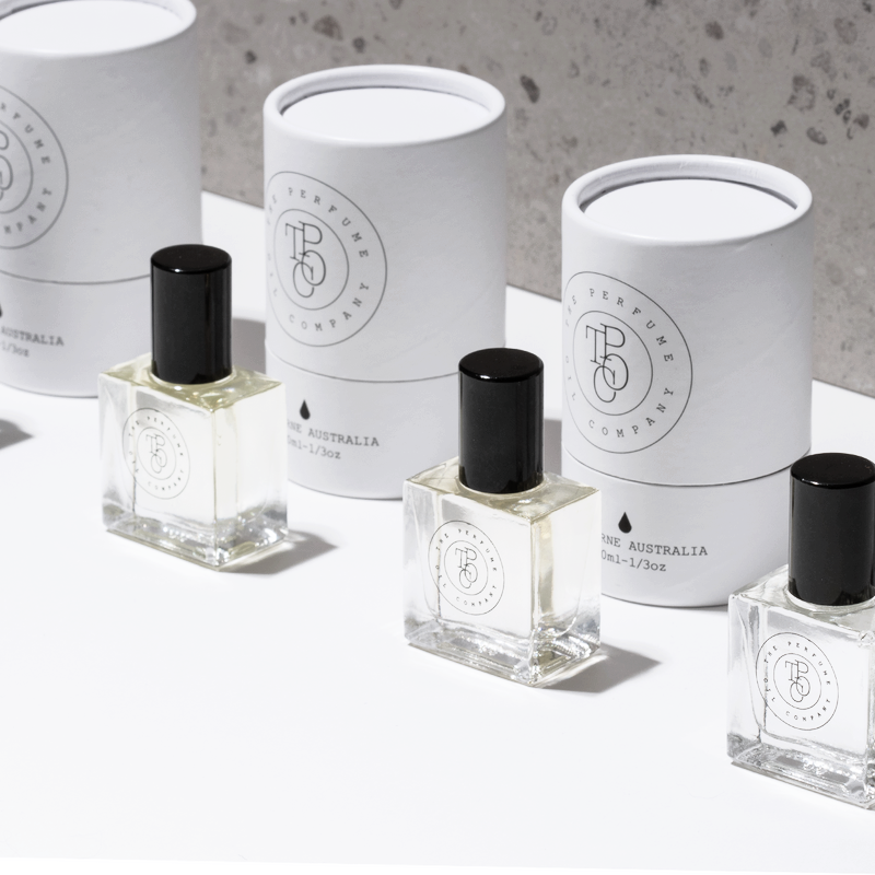 Four bottles of The Perfume Oil Collection Gift Set - Floral from The Perfume Oil Company, gracefully arranged on a white surface.