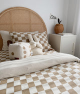 Kids bed with a rattan headboard, khaki gingham duvet cover and a dice cushion