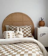 Khaki gingham check pillow and dice cushion at the head of a bed with matching bedding