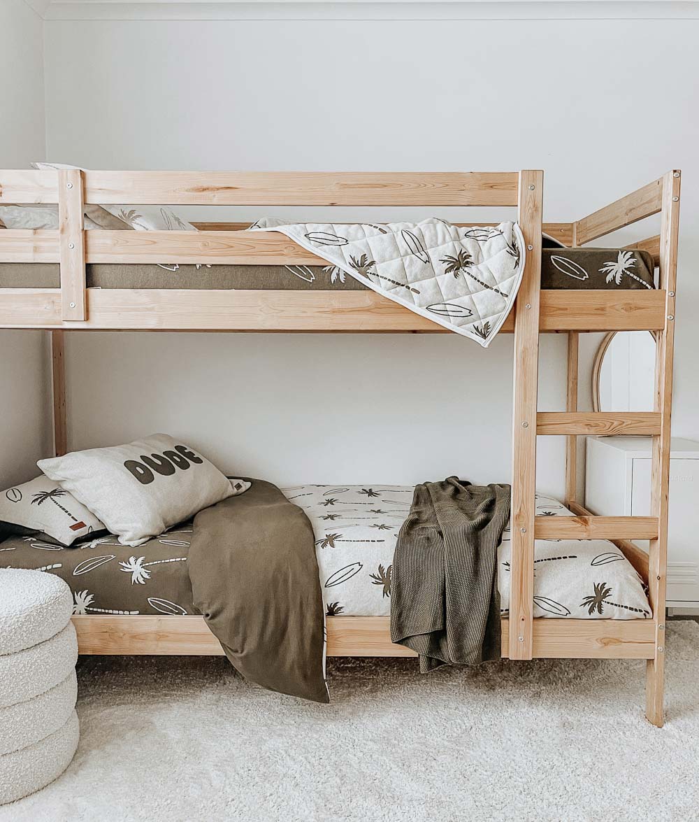 Timber bunk beds in olive Surfing Palm bedding, a Surfing Palm reversible quilt draped over the top bunk
