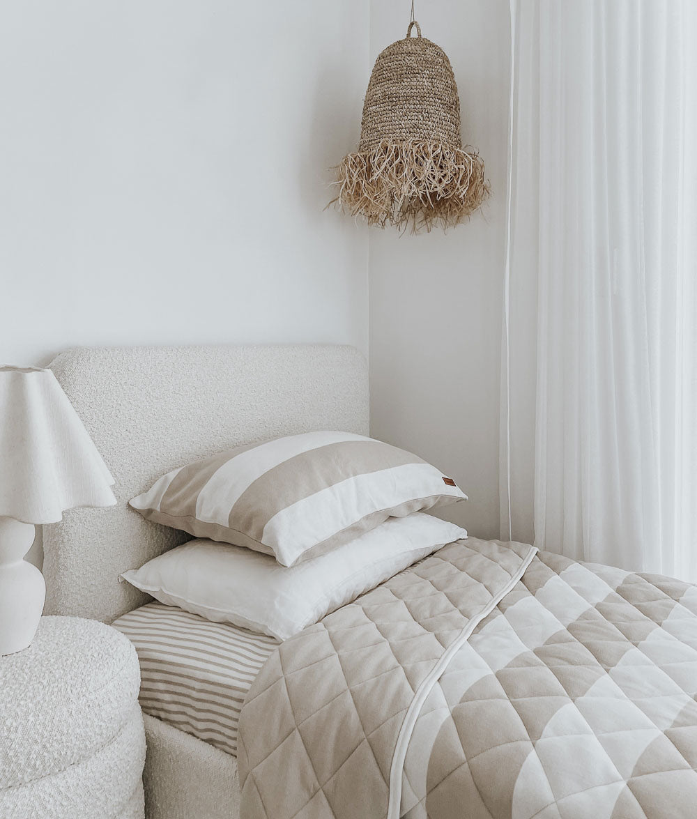 Boucle single bed with a greige pinstripe fitted sheet, wide stripe pillowcases and a greige stripe quilt