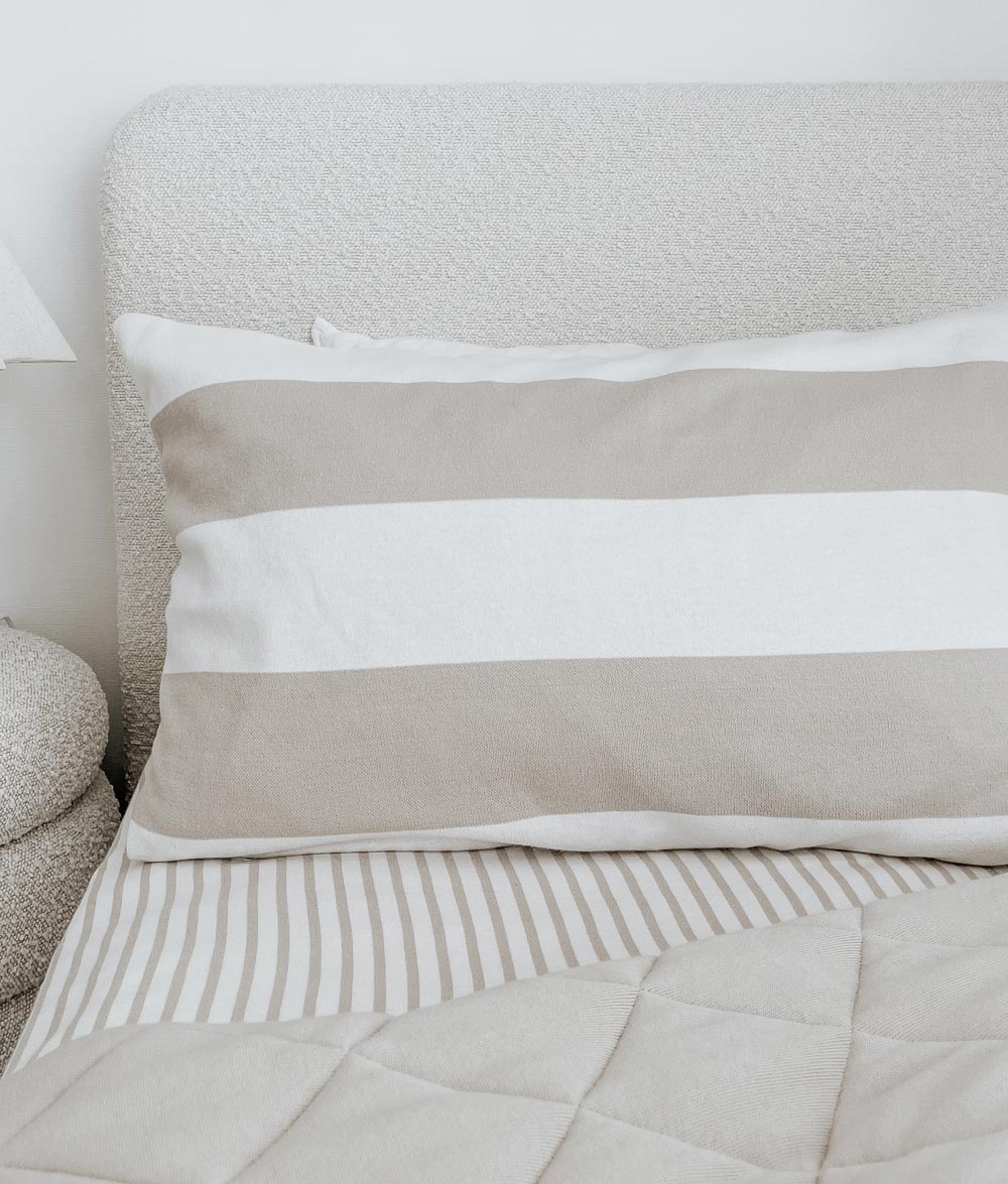 Wide stripe pillowcase on a boucle bed made up with a greige pinstripe jersey fitted sheet