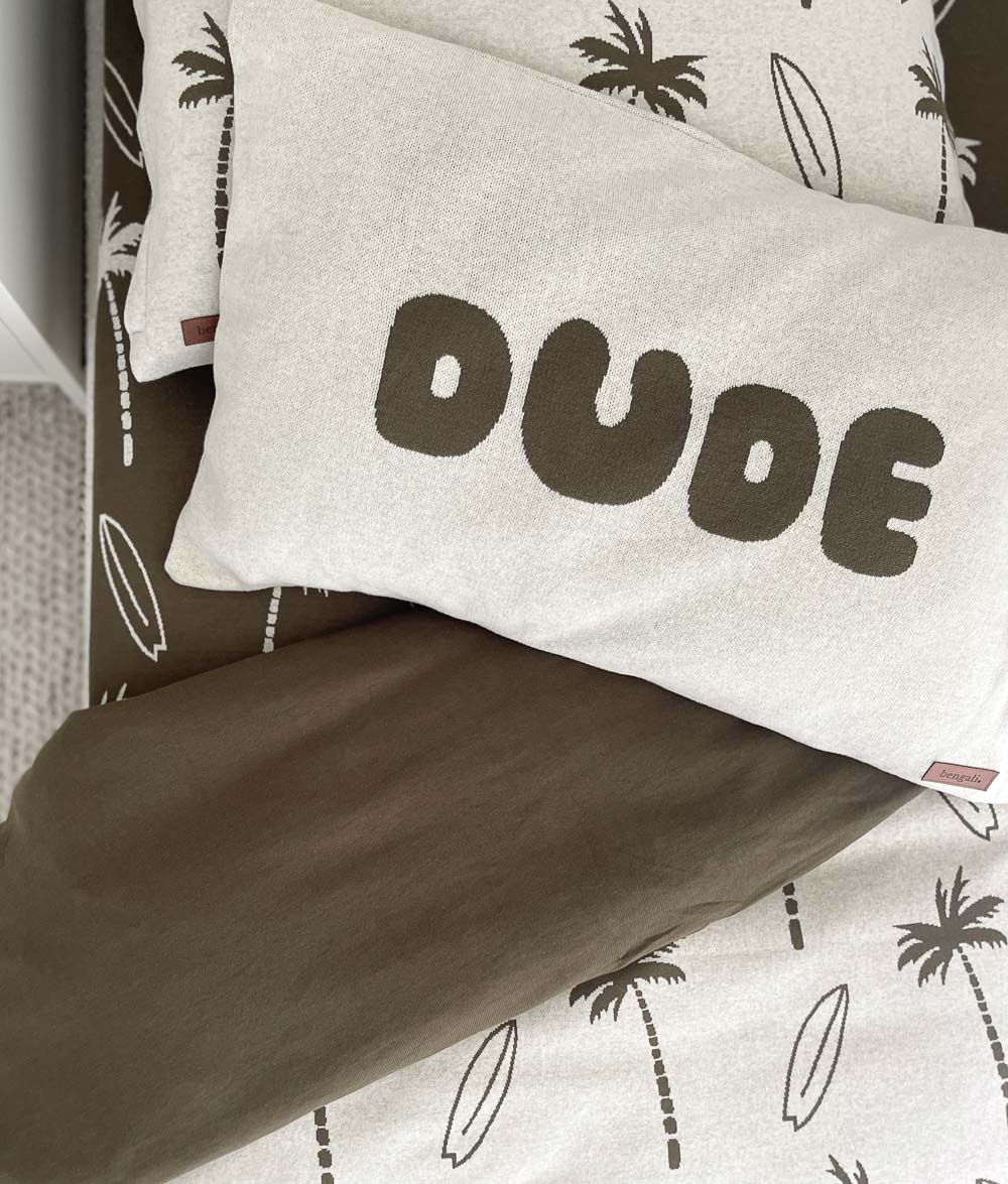 DUDE jersey cotton pillowcase with olive lettering resting on an olive and natural Surfing Palm bed