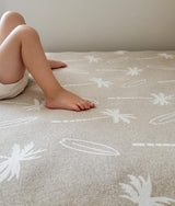 Close-up of a child kneeling on the dune fitted sheet showing the ivory palm print