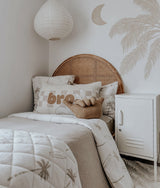 Kids bed with a bro check cushion, dune palm bedding and a white locker beside it