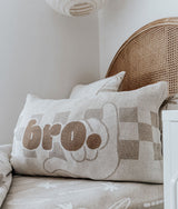 Bro check cushion propped on the dune palm fitted sheet beside a white locker
