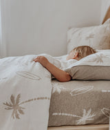 Child lying on the dune palm fitted sheet with matching palm bedding pulled up