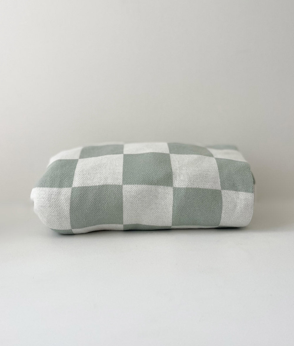 Rolled sage and ivory gingham quilt on a white backdrop