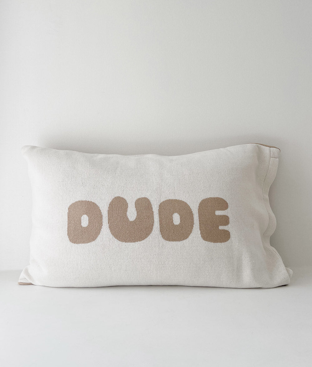 DUDE jersey cotton pillowcase with bold sand lettering, photographed front-on against a white wall