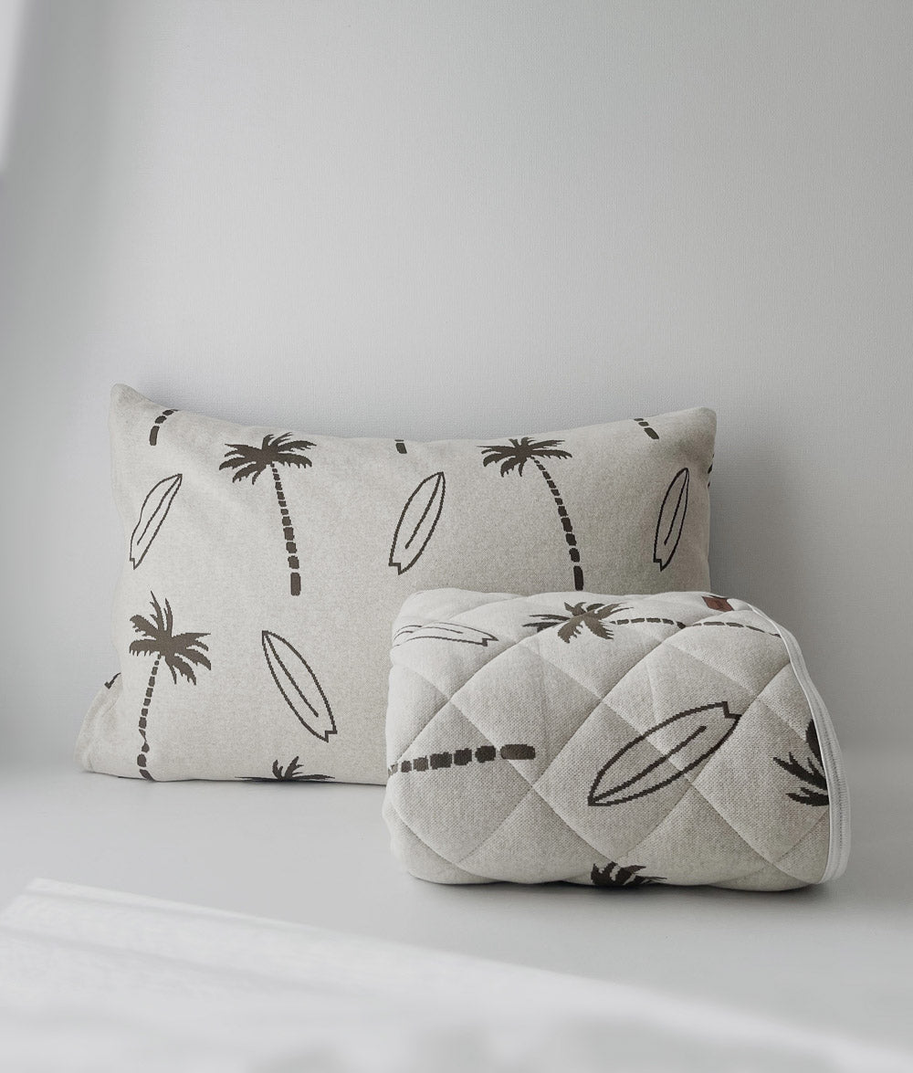 Rolled olive Surfing Palm reversible quilt in front of a matching Surfing Palm pillowcase