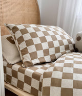 Khaki gingham check pillow on a rattan bed with the matching duvet cover