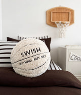 Basketball sherpa cushion on a chocolate duvet with striped pillows and a rattan hoop above