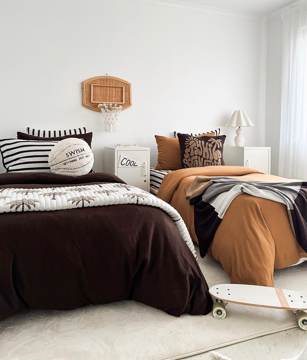 Boys bedroom with two beds, a skateboard on the floor and the basketball sherpa cushion on the bed