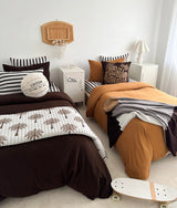 Two kids beds in chocolate and tobacco bedding with the basketball sherpa cushion at the head
