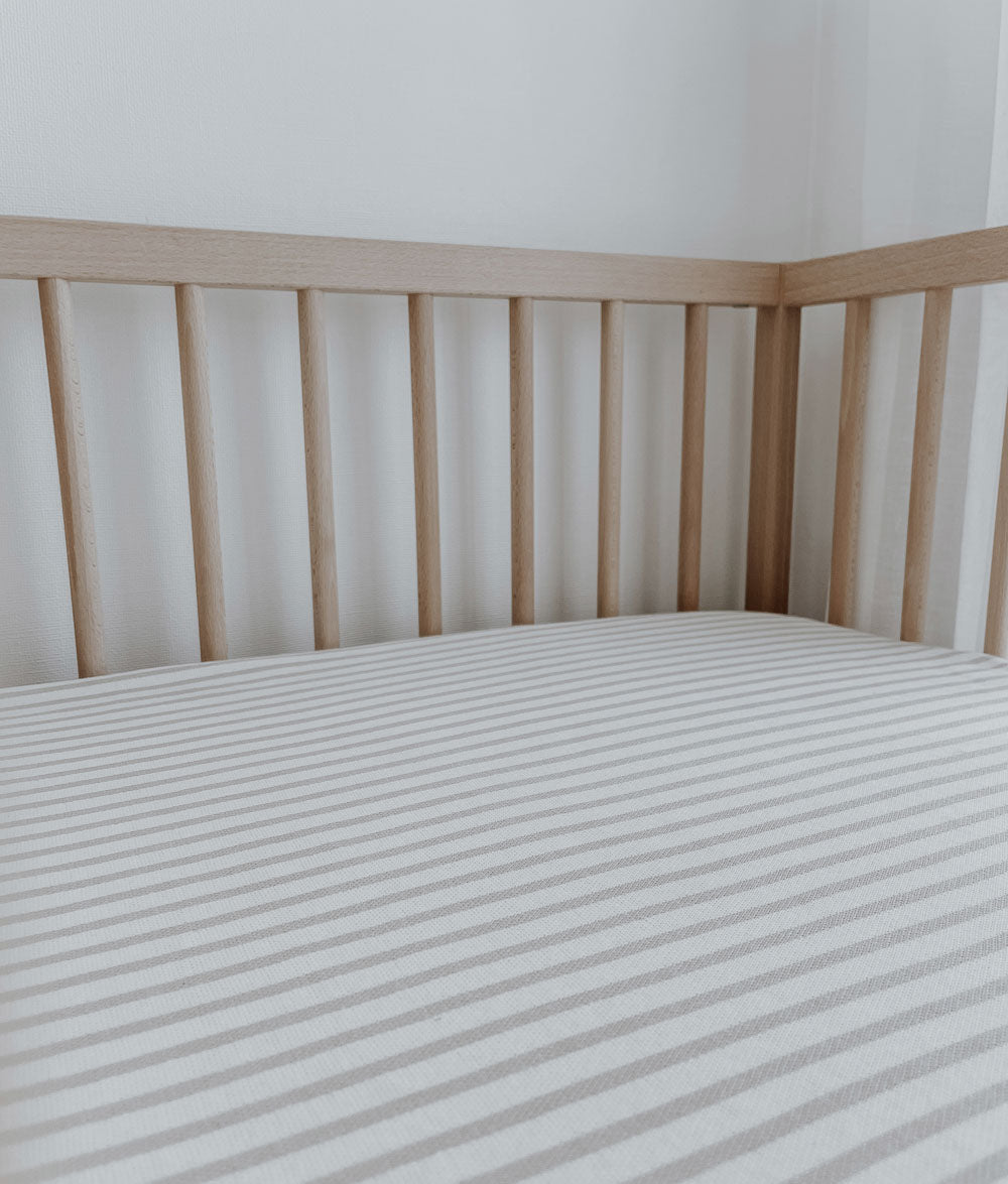 Greige pinstripe jersey cotton cot sheet in a timber cot