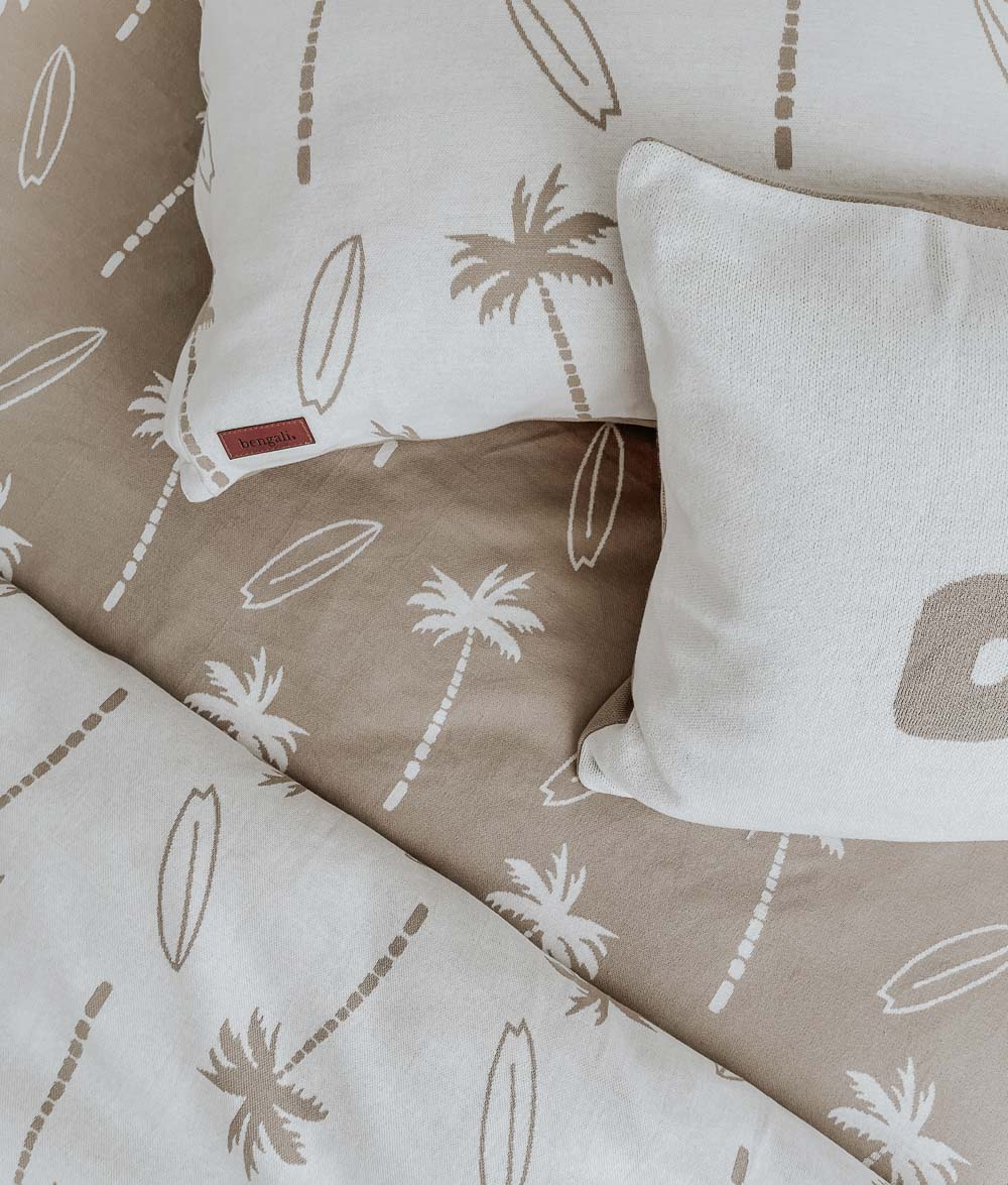 Sand Surfing Palm jersey fitted sheet with Surfing Palm and DUDE pillowcases over a natural duvet cover