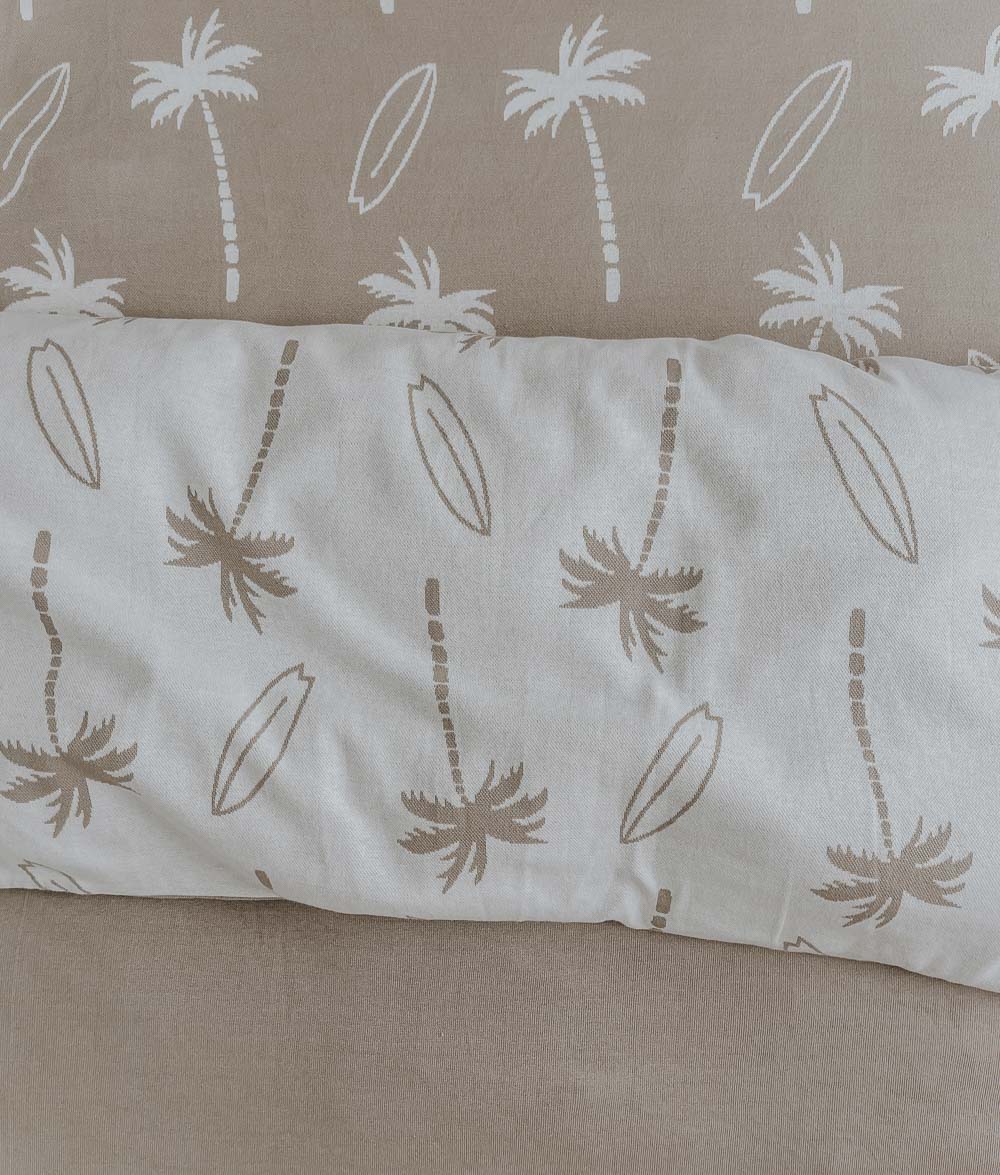 Close-up of a natural Surfing Palm duvet cover folded over a sand Surfing Palm jersey fitted sheet