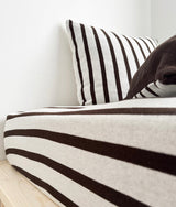 Striped euro pillowcase against a white wall with a chocolate Highland cow soft toy beside it