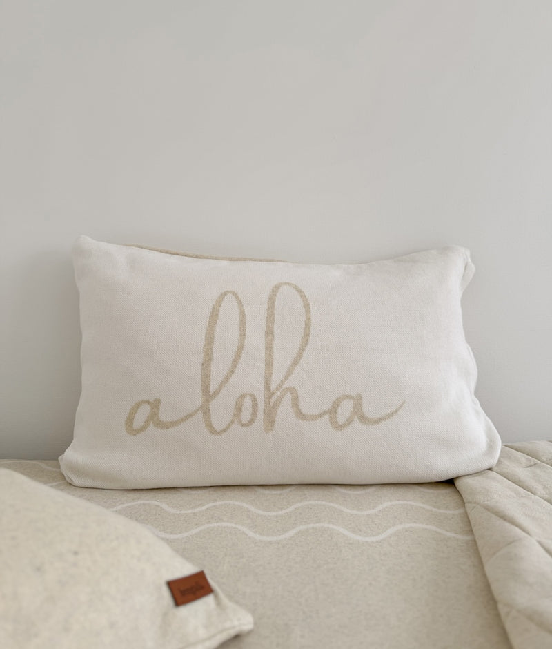 Aloha cotton pillowcase in ivory with natural script lettering and a leather label on a wave print sheet