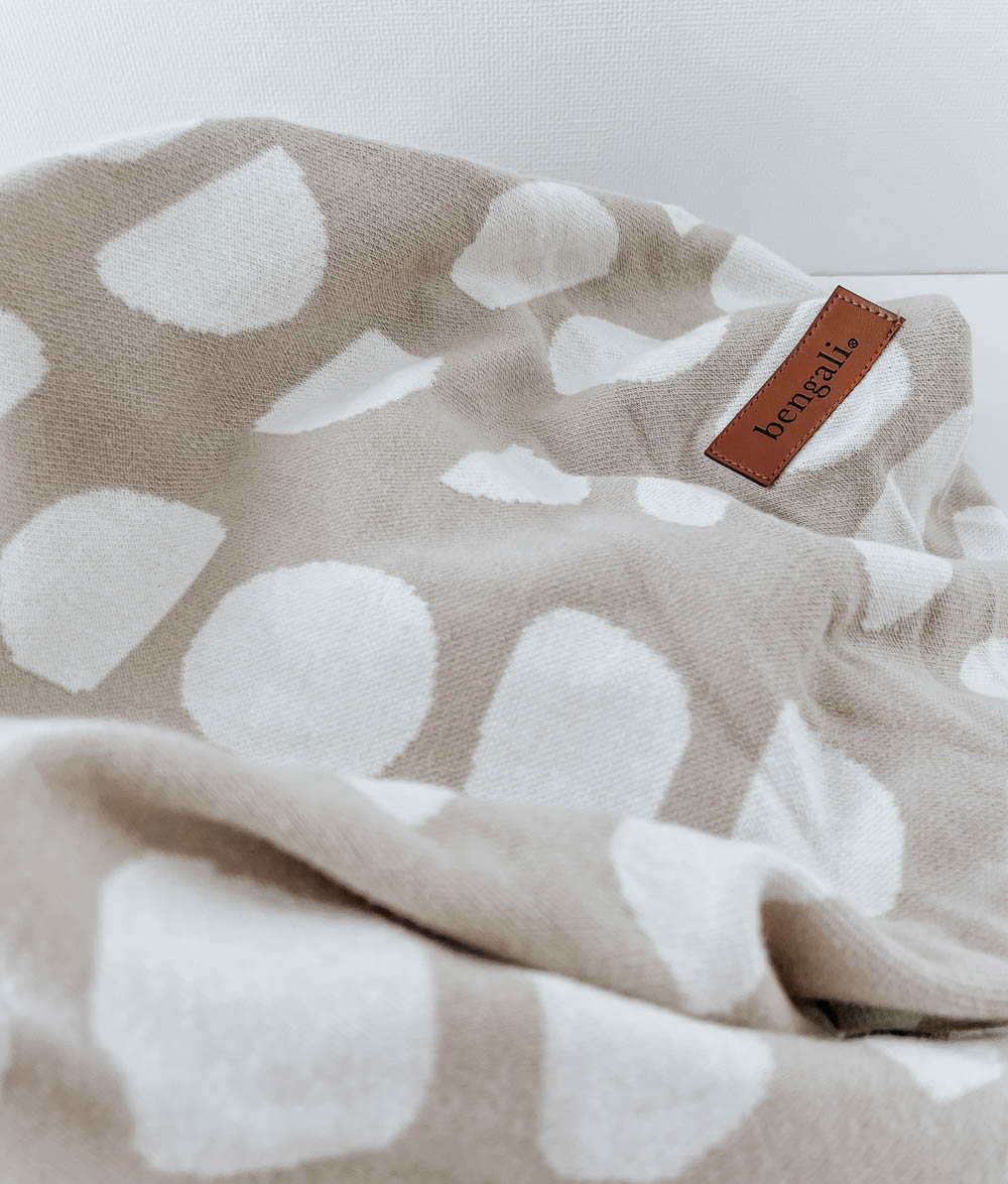 Close-up of the oatmeal Moon Phase jersey fitted sheet with ivory moons and a leather Bengali label