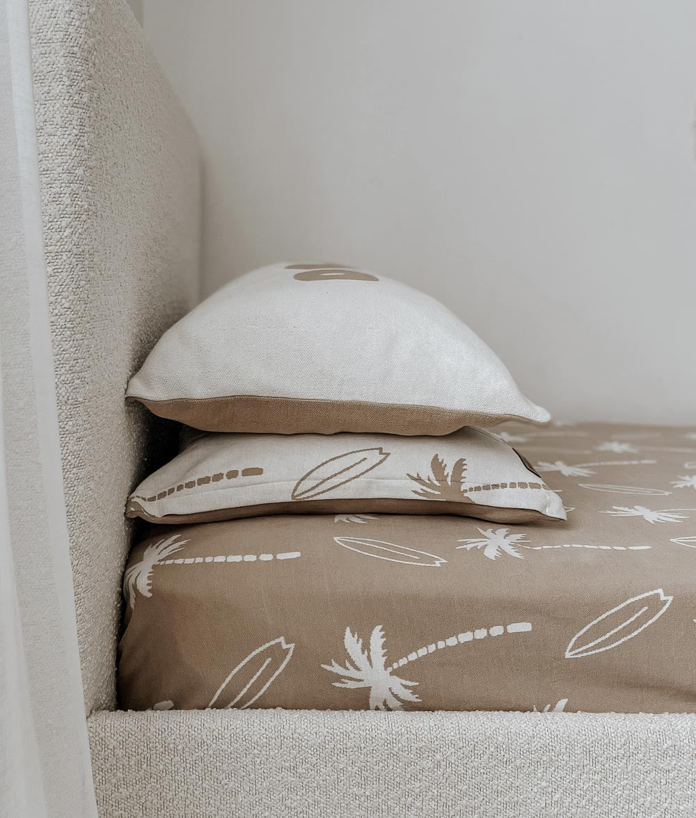Boucle bed dressed in a sand Surfing Palm jersey fitted sheet with matching Surfing Palm pillowcases