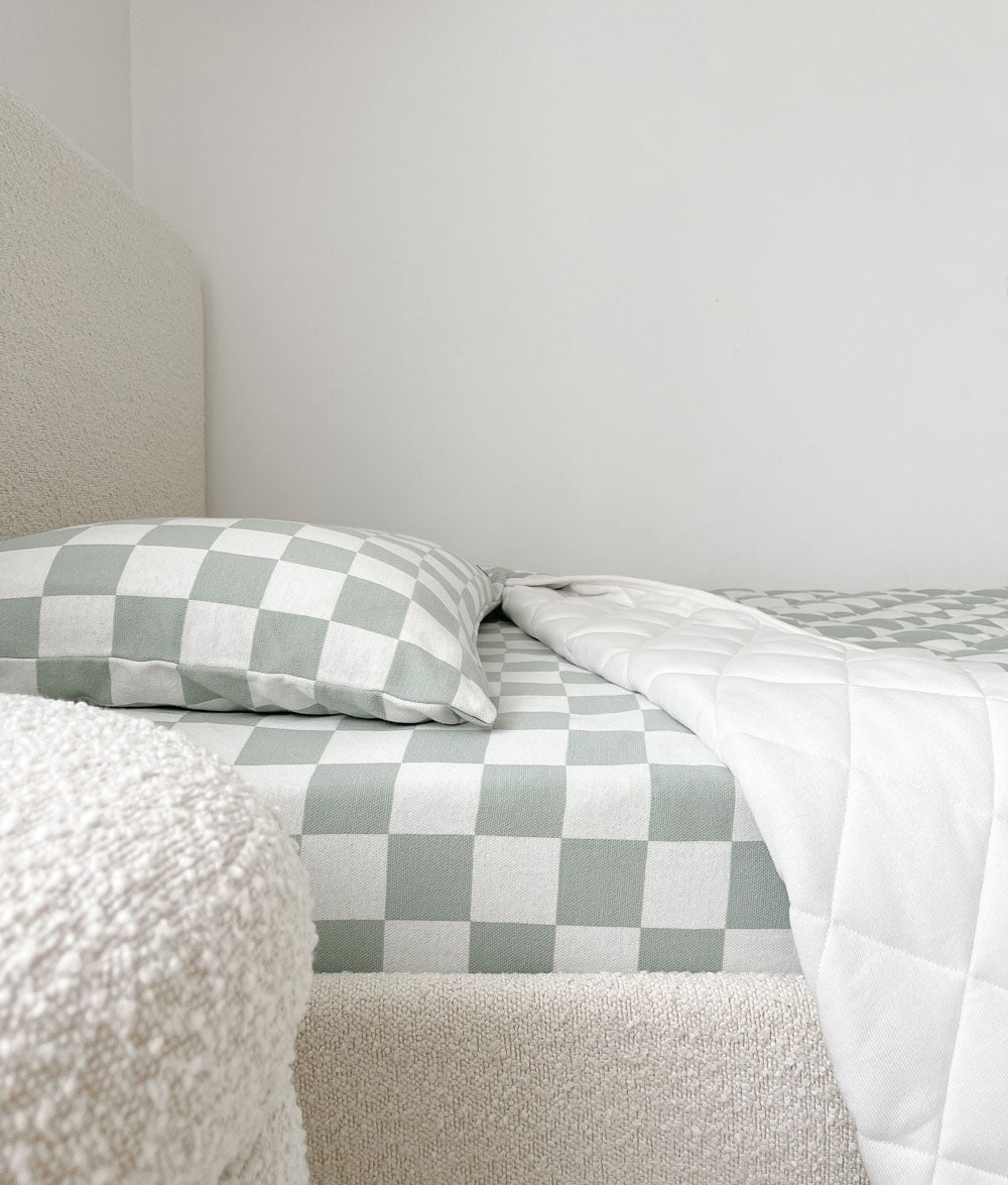 Boucle bed dressed in a Sage Gingham jersey fitted sheet with a matching pillowcase and white quilt