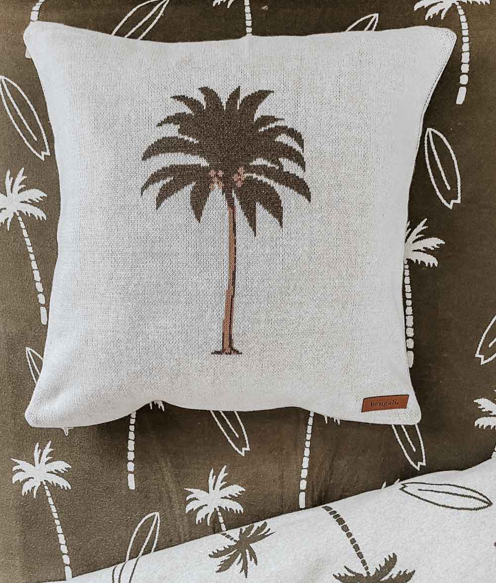 Palm tree cushion resting on an olive Surfing Palm jersey cotton fitted sheet