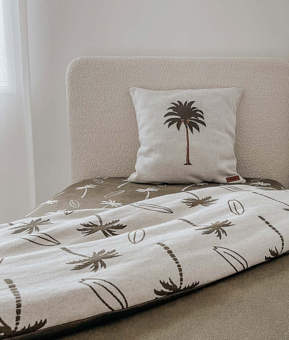 Kids bed with a Surfing Palm duvet cover in the olive print, palm tree cushion and boucle headboard
