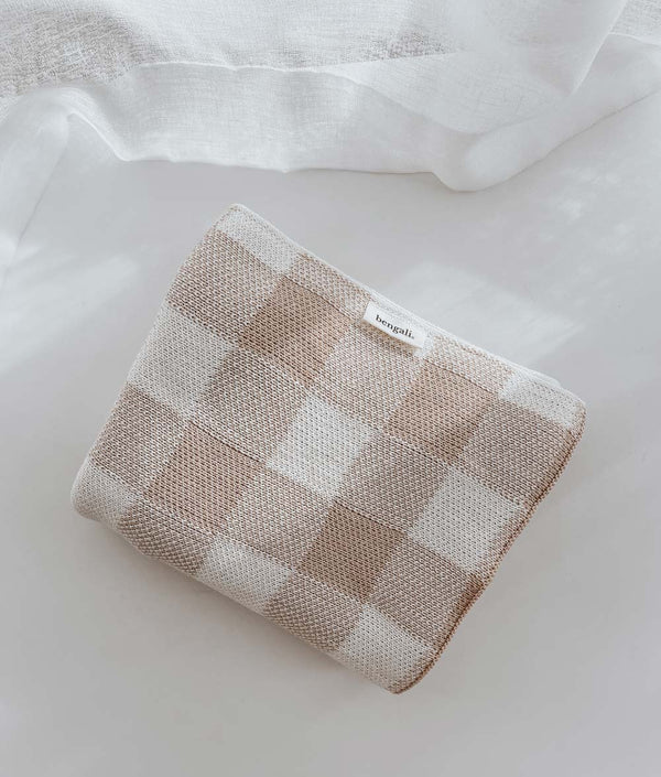 A TAN GINGHAM BABY BLANKET from Bengali Collections on a bed.