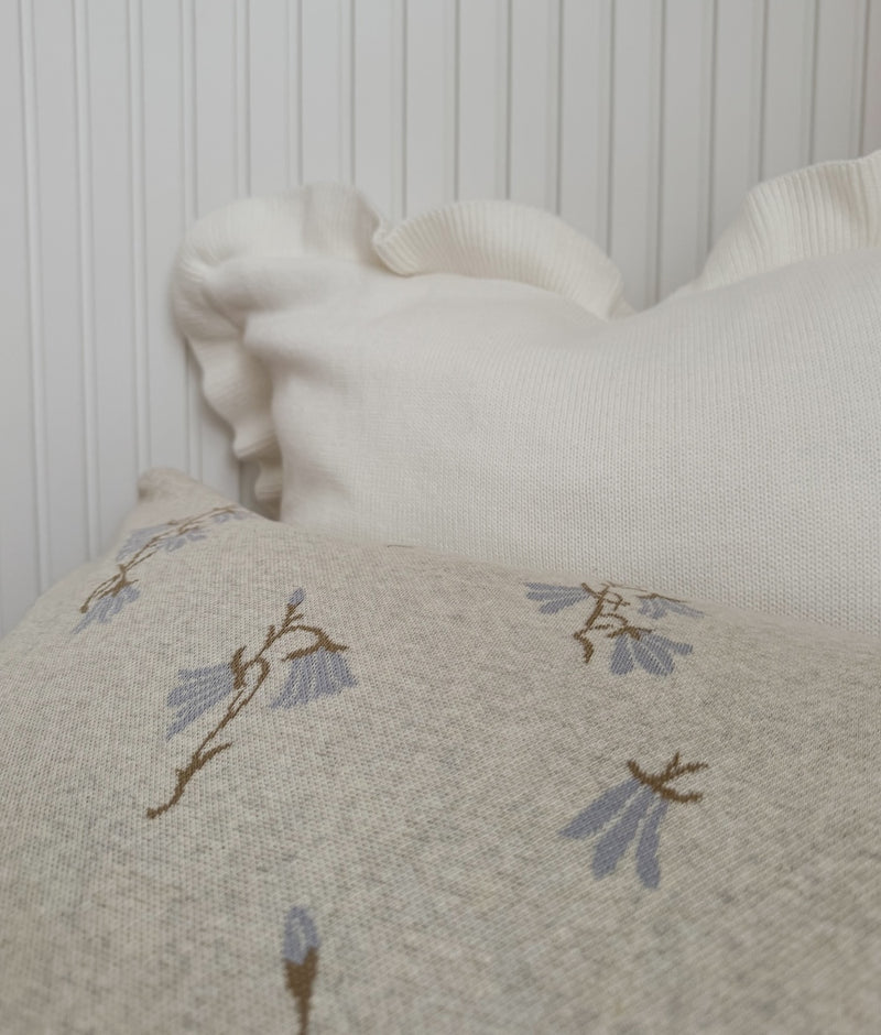 Close-up of the Ivory Frill euro pillowcase behind a bluebell print pillowcase against white panelling