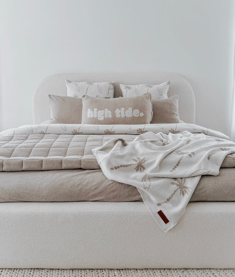 Bed styled with a dune Surfing Palm knitted blanket, greige quilt and a High Tide pillowcase