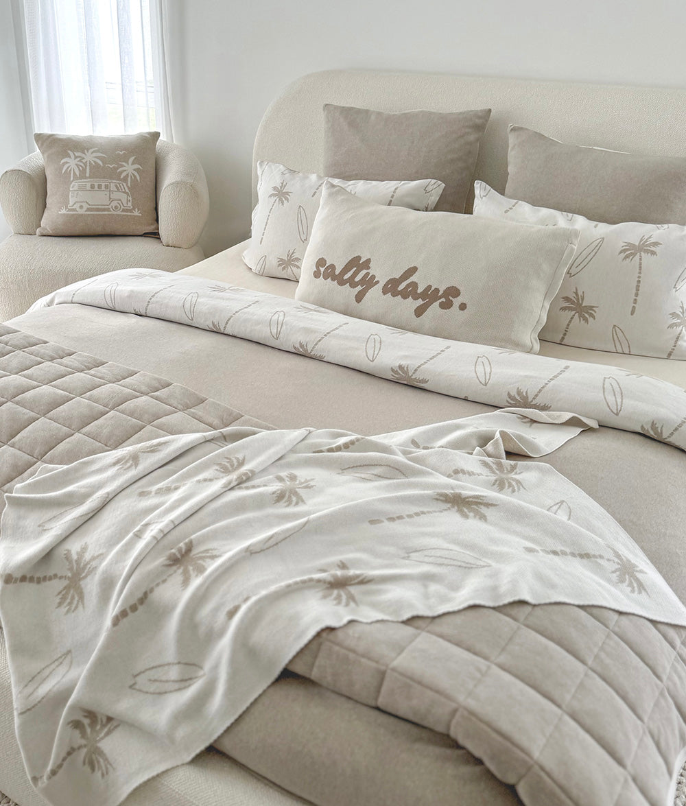 Bed styled with a salty days cushion, palm print bedding and the dune quilt