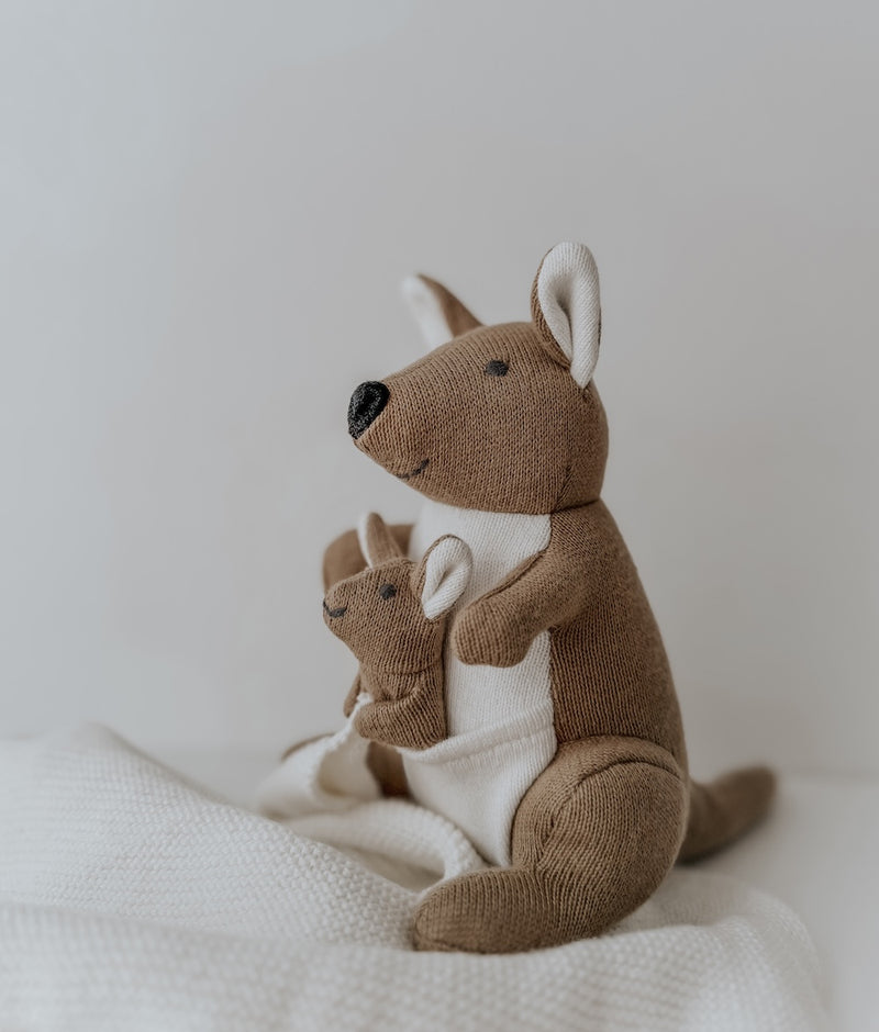 Side view of the Kangaroo baby comforter snuggly with its joey, on a white knit blanket