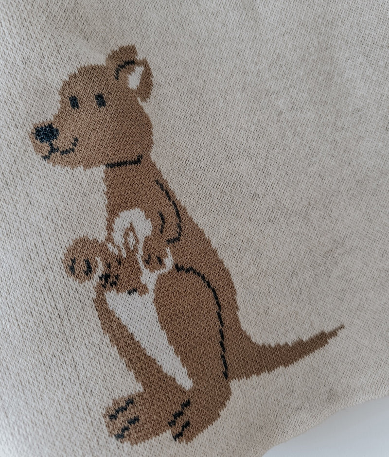 Close-up of the khaki kangaroo with a joey in her pouch knitted into the natural marle baby blanket