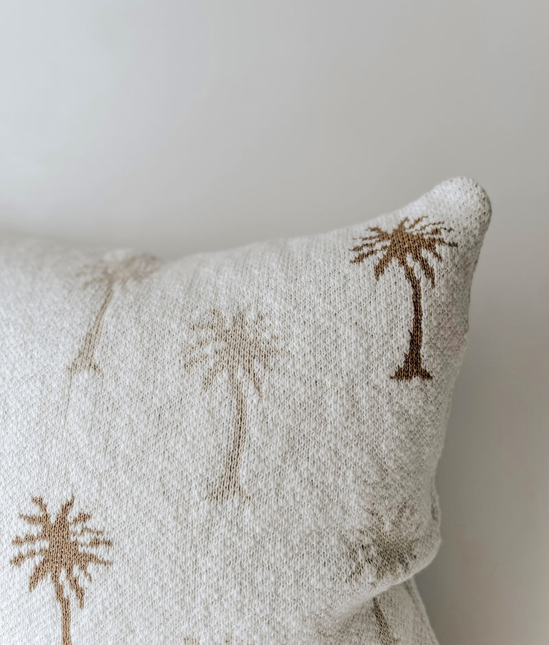 Close-up of natural and khaki palm trees on the textured ivory cotton of the Palma cushion cover