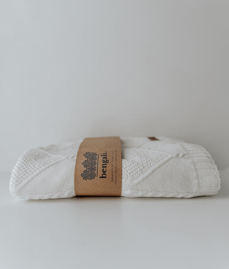 Folded Ivory Diamante lounge throw with its Bengali paper band on a white backdrop