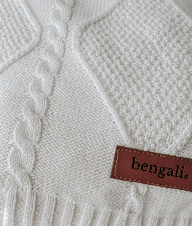 Close-up of the Ivory Diamante throw's cable and diamond knit texture and leather Bengali label