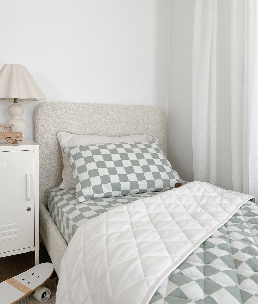 Boucle single bed with a Sage Gingham reversible quilt turned to ivory, matching pillowcase and skateboard