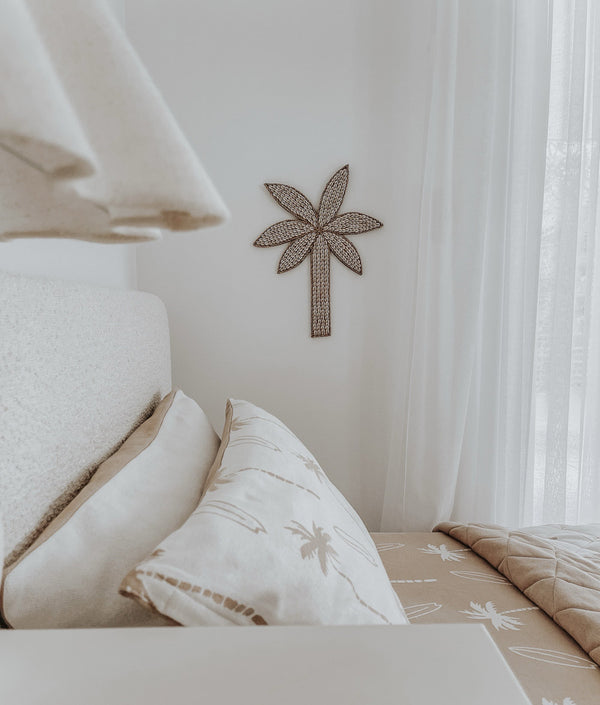 Natural Surfing Palm kids pillowcases on a boucle bed beside a woven palm tree wall hanging